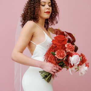 Bash By BLVD Revelle x Maide Bride holding red bouquet wearing fitted wedding gown Layla minimalist wedding dress