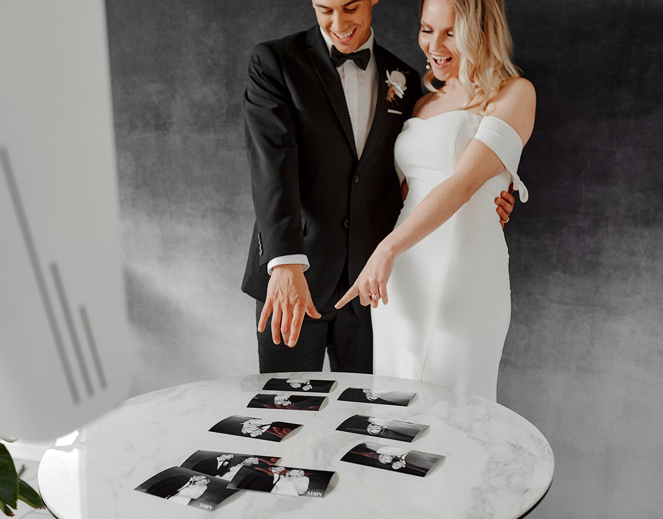 Bash by Revelle Bridal Ottawa MDRN Photo Booth Bride and Groom Looking at Printed Photographs Mementos Wedding Favours Fun Entertaining
