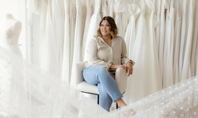 Revelle Bridal Boutique Owner Earleen in front of wedding dress rack - let's talk about consultations blog