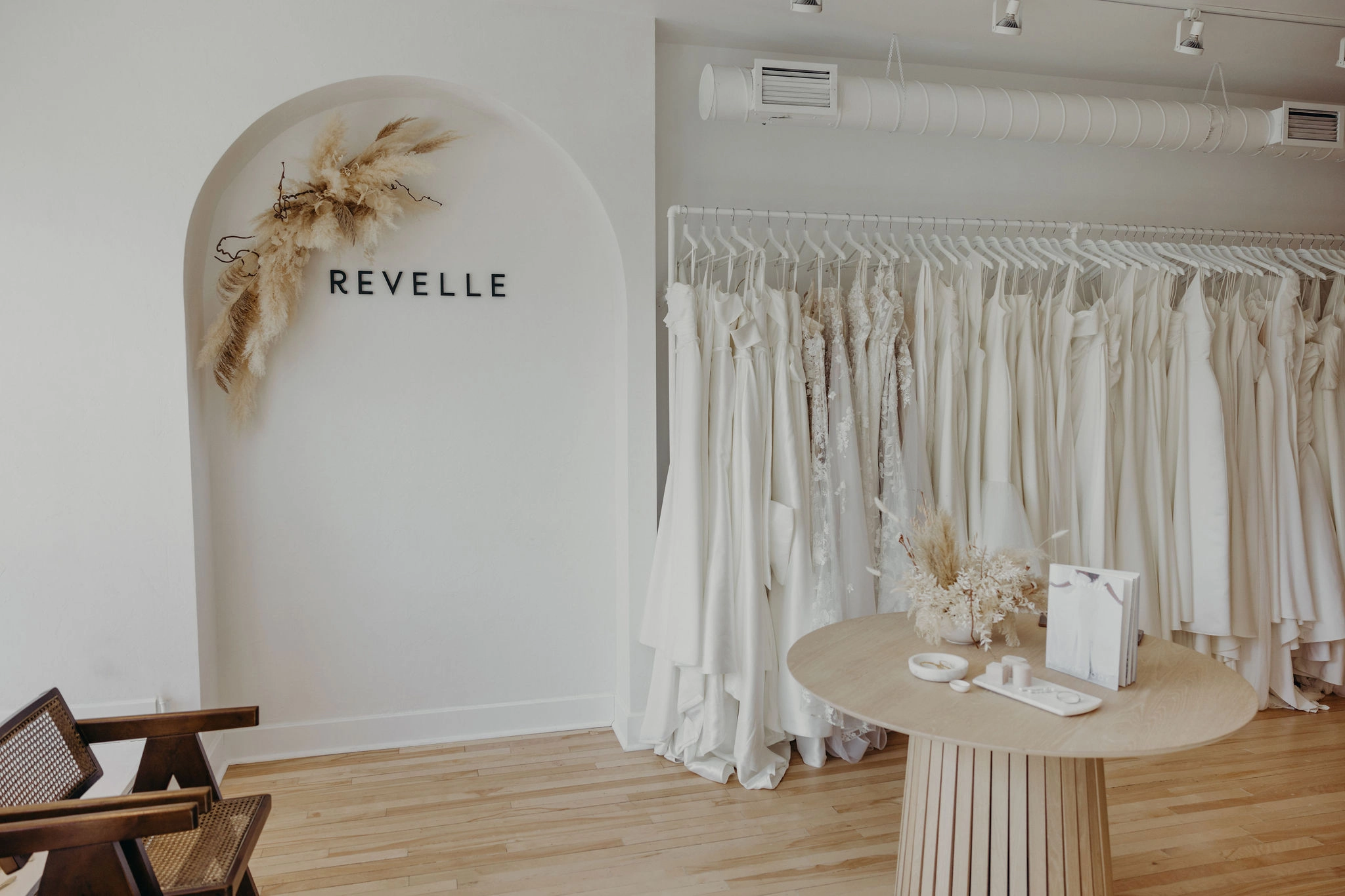 Revelle Bridal Ottawa - Wedding Dress Shop - Luxury Wedding Boutique Westboro - Entrance Dress Rack, Arch, Wedding Dresses Chic Minimalist elegant space